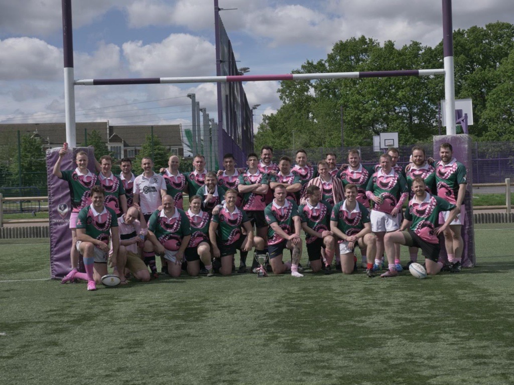 group of alumni all sat on a rugby pitch